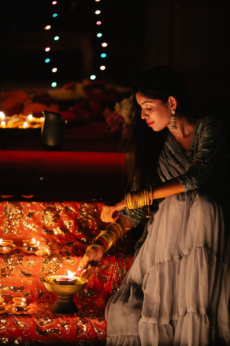 A woman lighting a diya among candles.