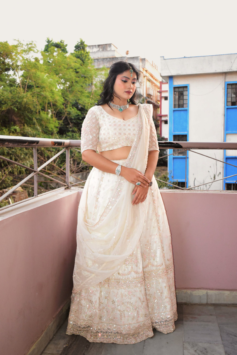 An ivory chikankari lehenga on a balcony.