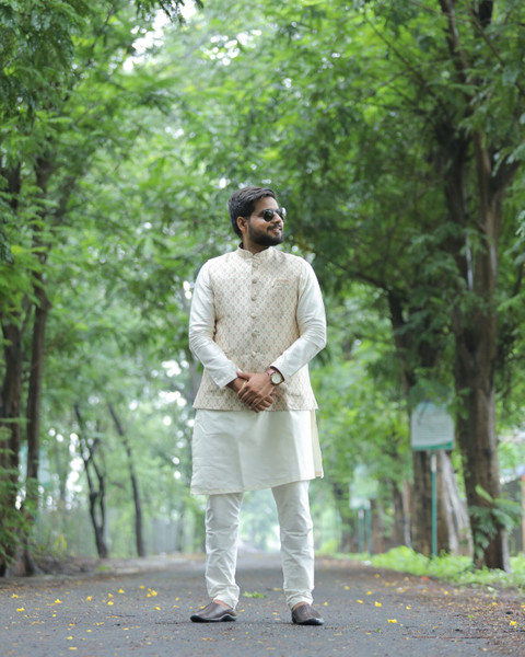 An ivory kurta with a Nehru jacket on a tree-lined road.