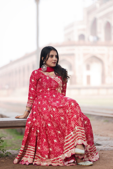 A red bandhani anarkali with a dupatta at an old tomb's garden.