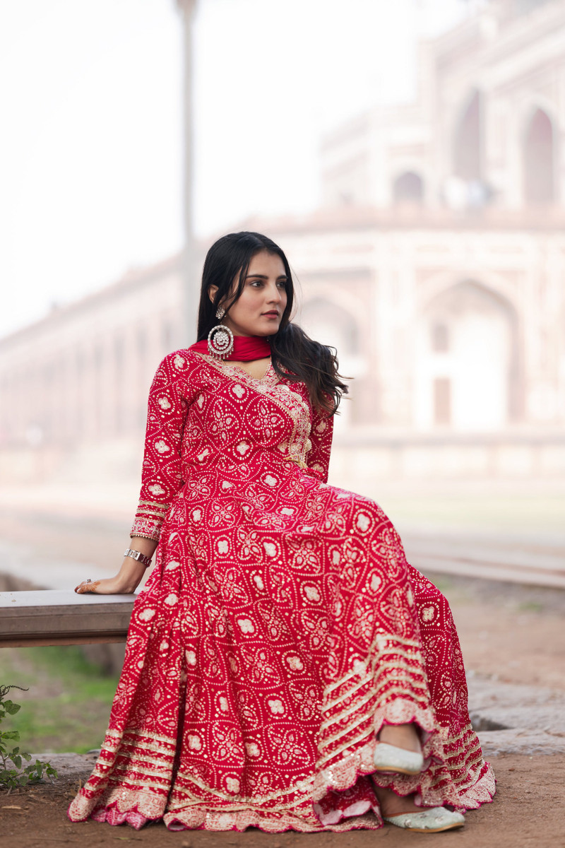 A red bandhani anarkali with a dupatta at an old tomb's garden.