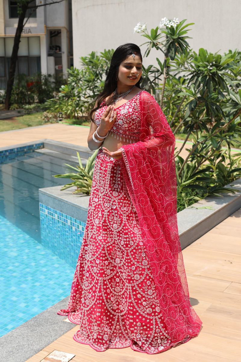 The rani pink lehenga, full length, the dupatta over the arm.