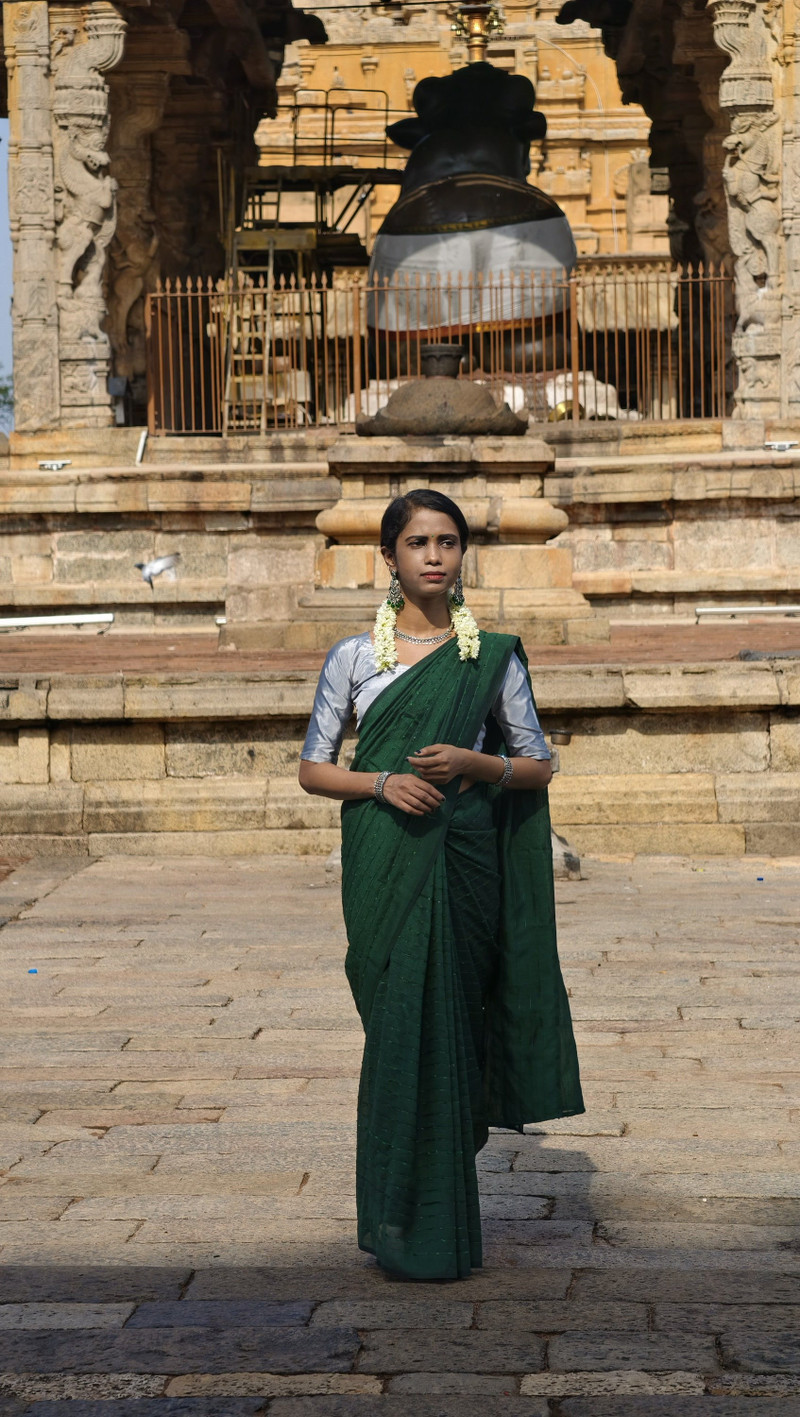 An emerald silk saree at a stone temple gateway.