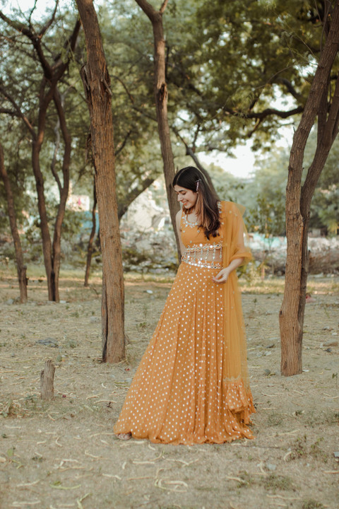 A marigold sequin lehenga among trees.