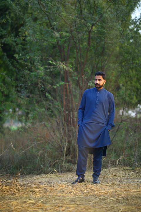 A royal blue pathani suit on a forest path.