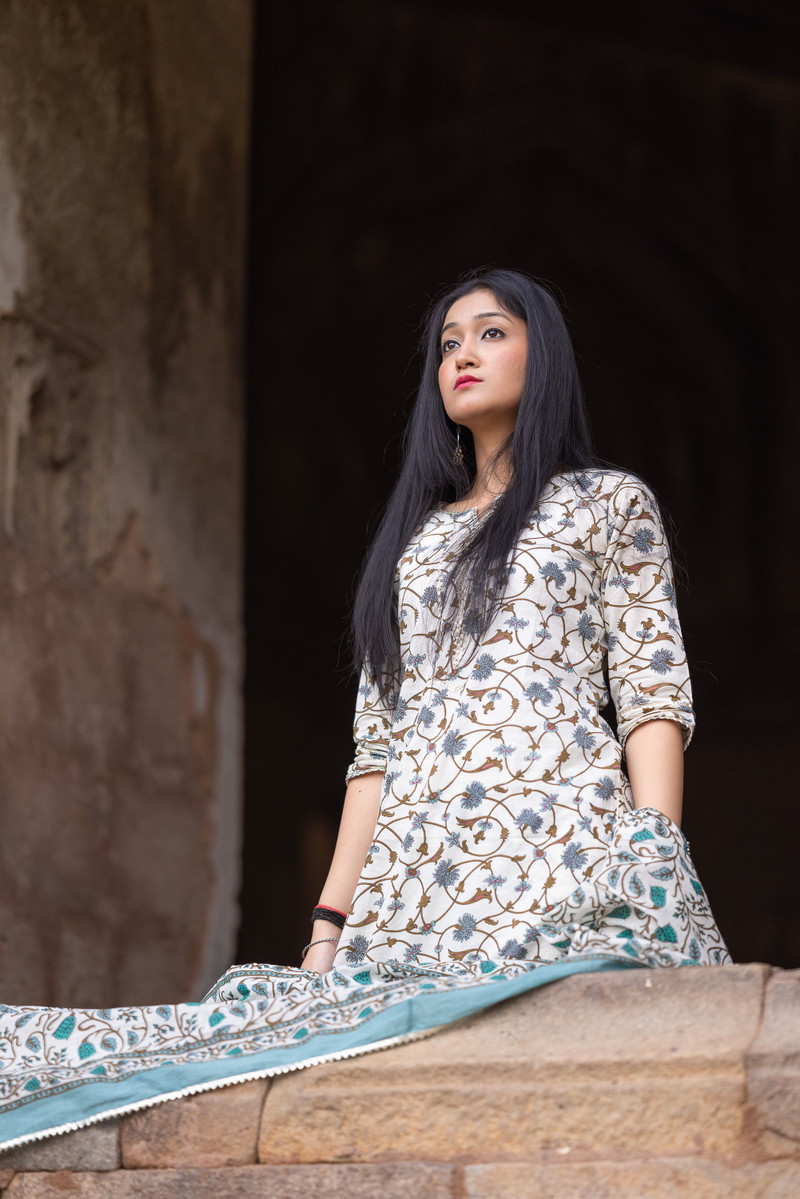An ivory floral-print kurta with a dupatta in a stone doorway.