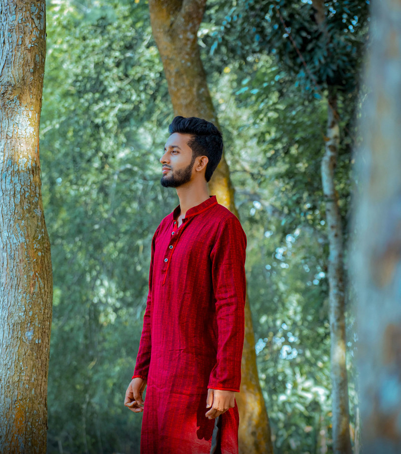 A red silk kurta in a green forest.